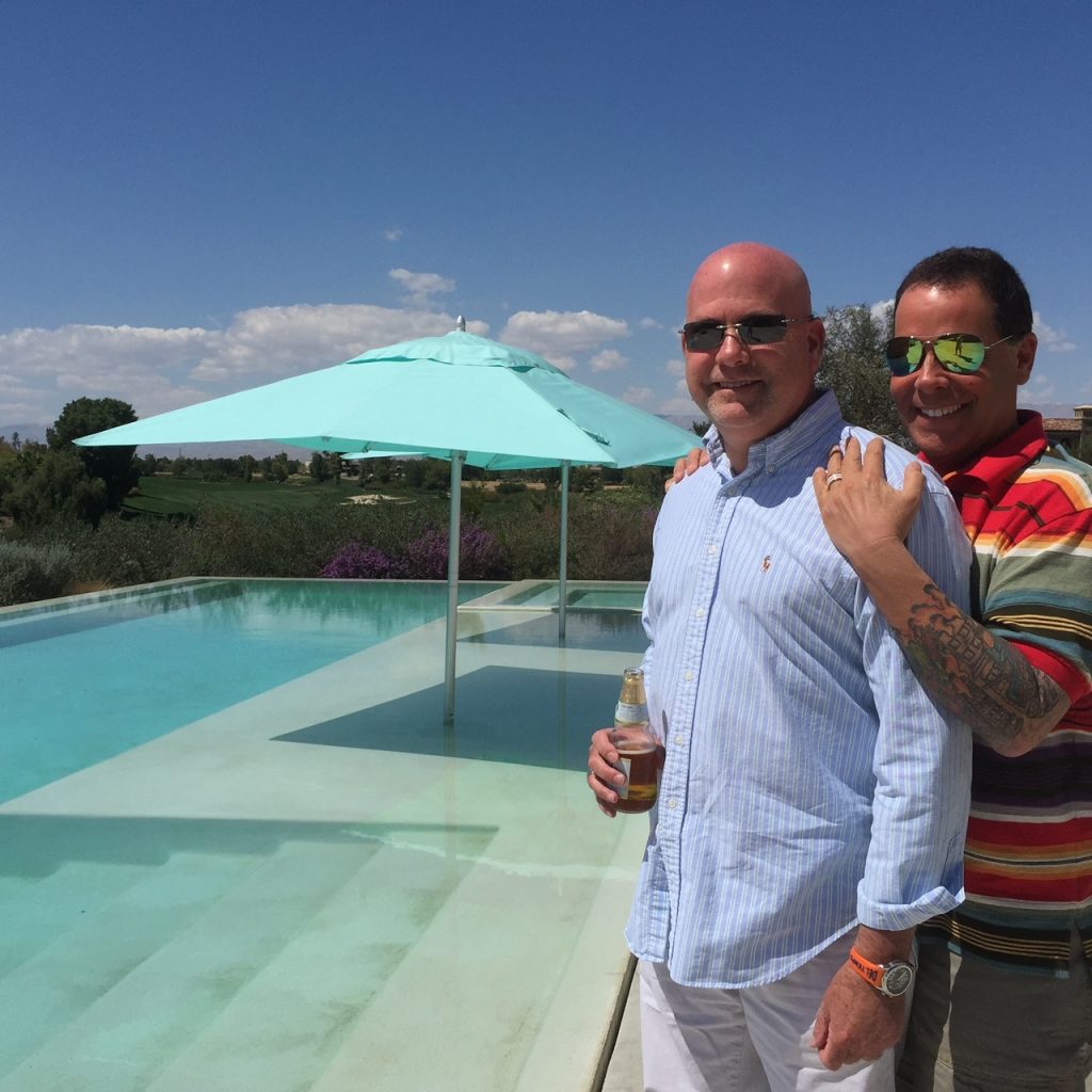 Jim and Kevin in front of a pool standing and smiling.
