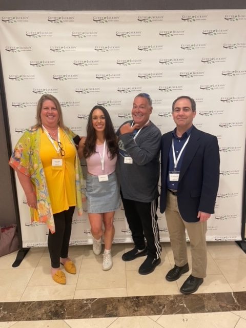 Julia Lefelar, Caitlin Jo Burke, Jim Broutman and Michael Levy pose in front of the Guthy Jackson NMO Patient Day step-and-repeat.