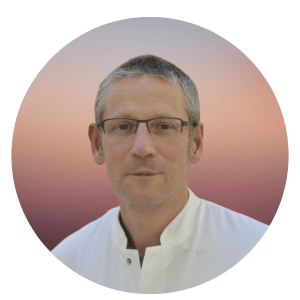 Prof. Dr. Friedemann Paul is shown with short grey hair, glasses and wearing a white button down shirt.