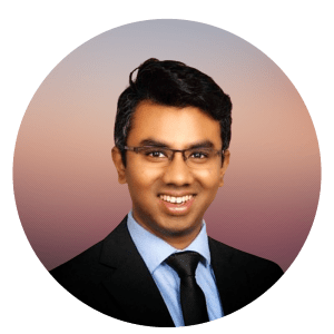 Dr Akash Virupakshaiah is shown smiling. He has medium skin tone, dark hair and glasses and is wearing a suite and tie with a white shirt.