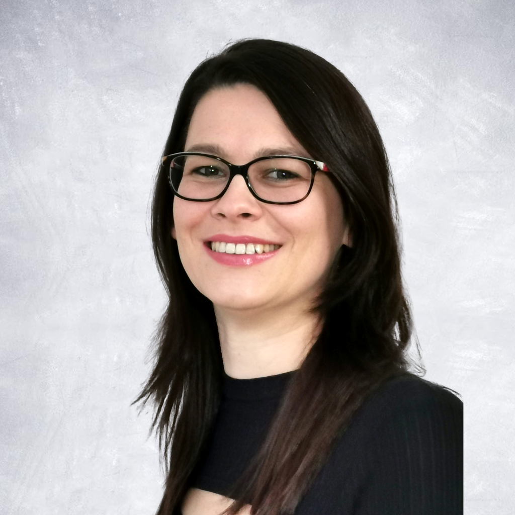 Maria Hasterman is shown with dark hair and dark glasses, smiling